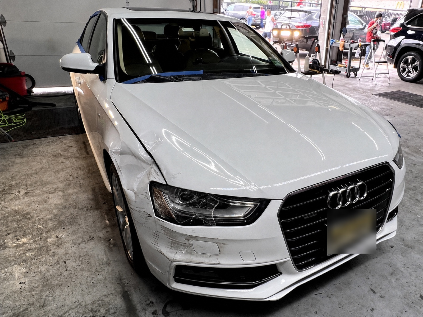 Audi with front-end collision damage — crumpled fender and scuffed bumper — before repair