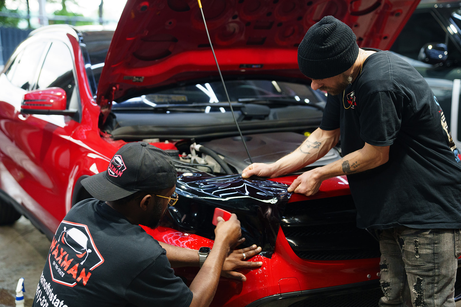 Waxman technicians working on the front end of a red Mercedes SUV in the Jersey City shop