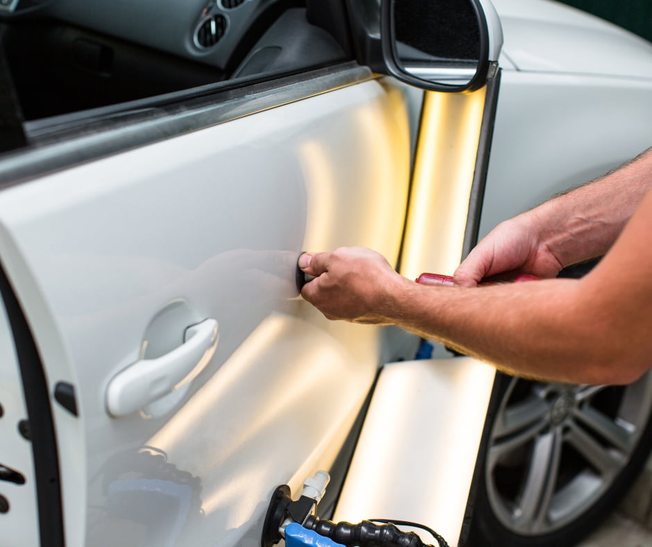 Paintless dent repair tools working a white door panel