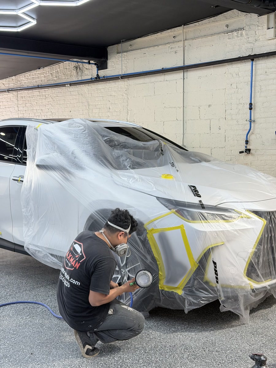 Waxman technician sanding a masked front fender before refinishing