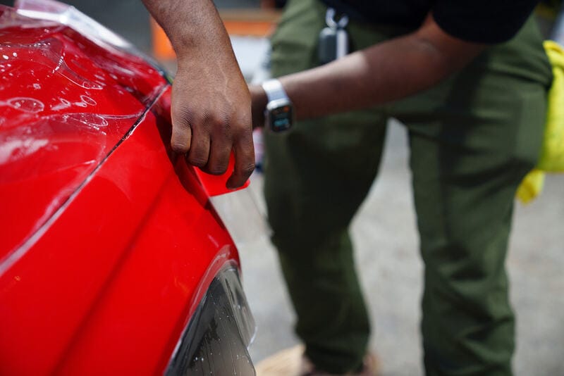 Paint protection film being squeegeed onto a hood panel