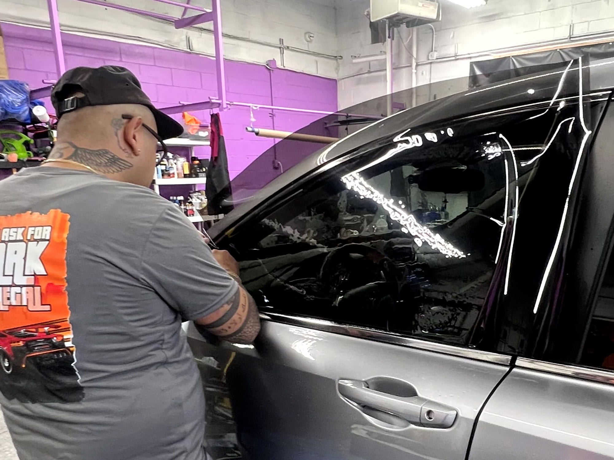 Installer applying tint film to a car door window